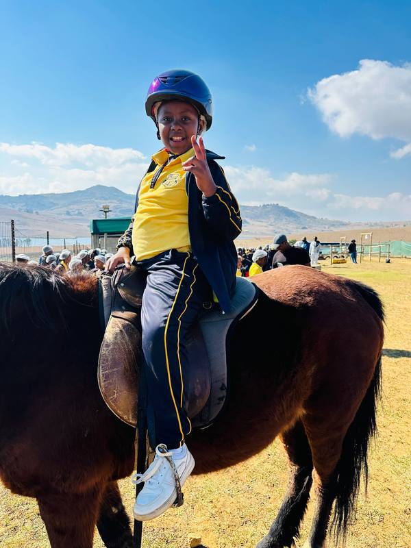A pupil riding a horse with hills in the background
