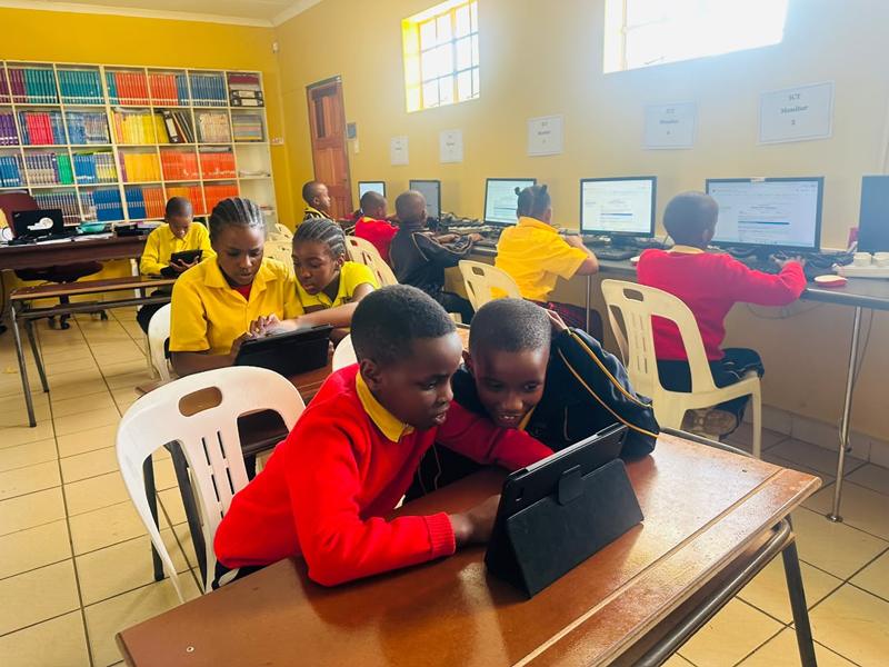 A class working at desktop computers and tablets in the ICT room