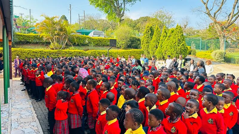 Rows of pupils in red school jerseys at the outdoor assembly